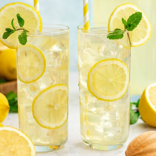 Two tall glasses of lemonade with lemon slices and mint sprigs