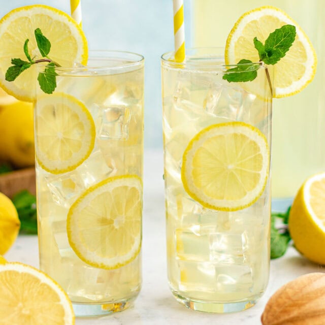 Two tall glasses of lemonade with lemon slices and mint sprigs