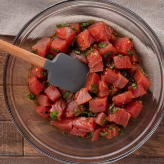 Sauce and chopped raw tuna in bowl with spatula