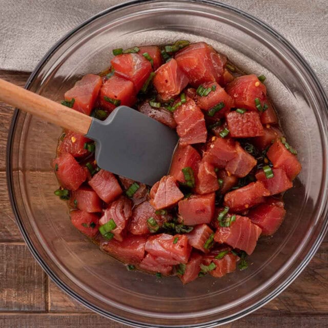 Sauce and chopped raw tuna in bowl with spatula
