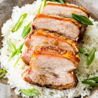 Dinner plate with sliced meat on a bed of rice.