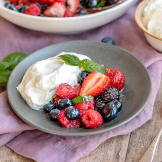 Bowl of blueberries, strawberries, and raspberries, and whipped cream.