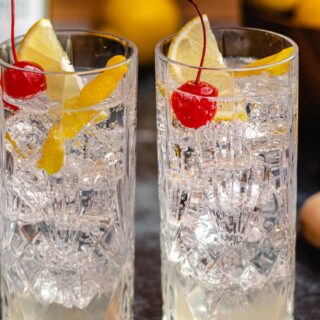 Two collins glasses filled with gin, club soda, and sweetened lemon juice.