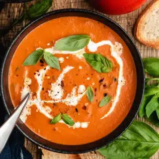 bowl of soup topped with basil and cream