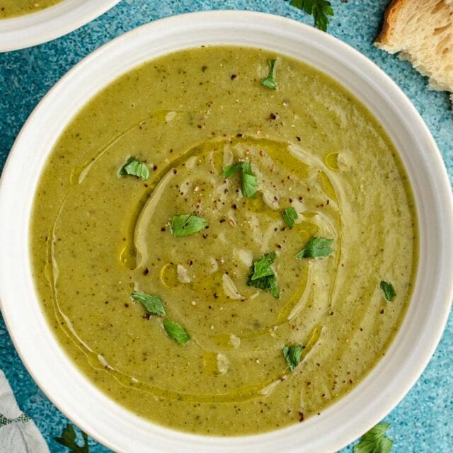 Bowl of soup with drizzle of oil and parsley on top.