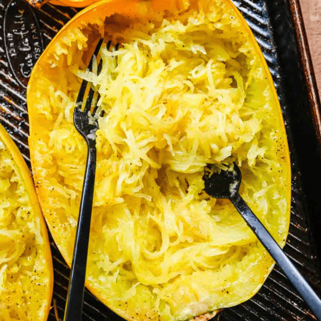 Roasted squash shredded with forks in shell on baking sheet