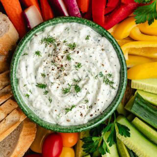 Bowl of herb dip with veggies fanned around it.