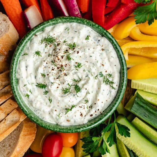 Bowl of herb dip with veggies fanned around it.