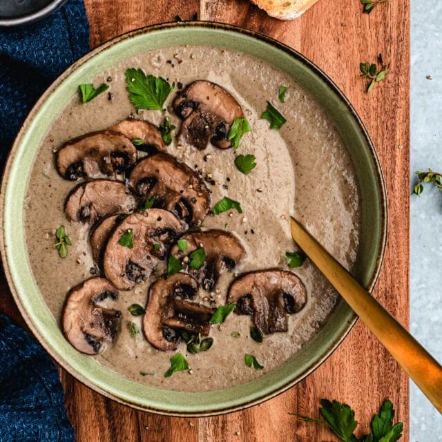 Bowl of creamy soup with mushrooms garnished on top.