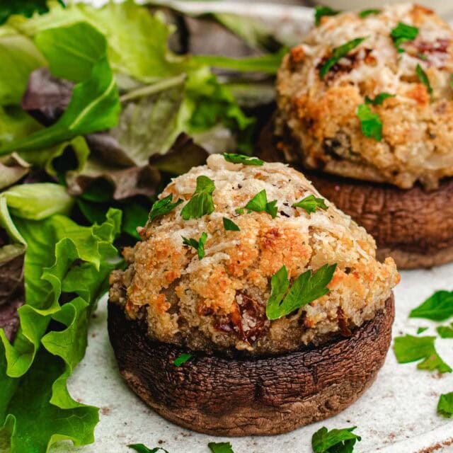 Baked stuffed creminis on dinner plate with side salad.