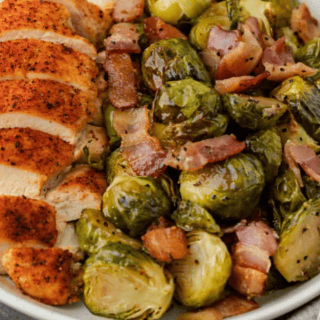 Cooked sprouts with bacon on plate with sliced chicken breast