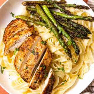 Dinner plate with sliced chicken, asparagus, and pasta.