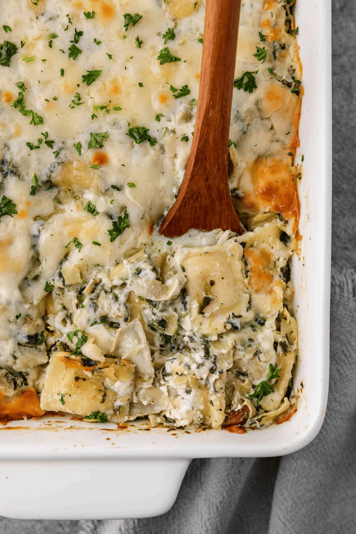 wooden spoon scooping ravioli bake