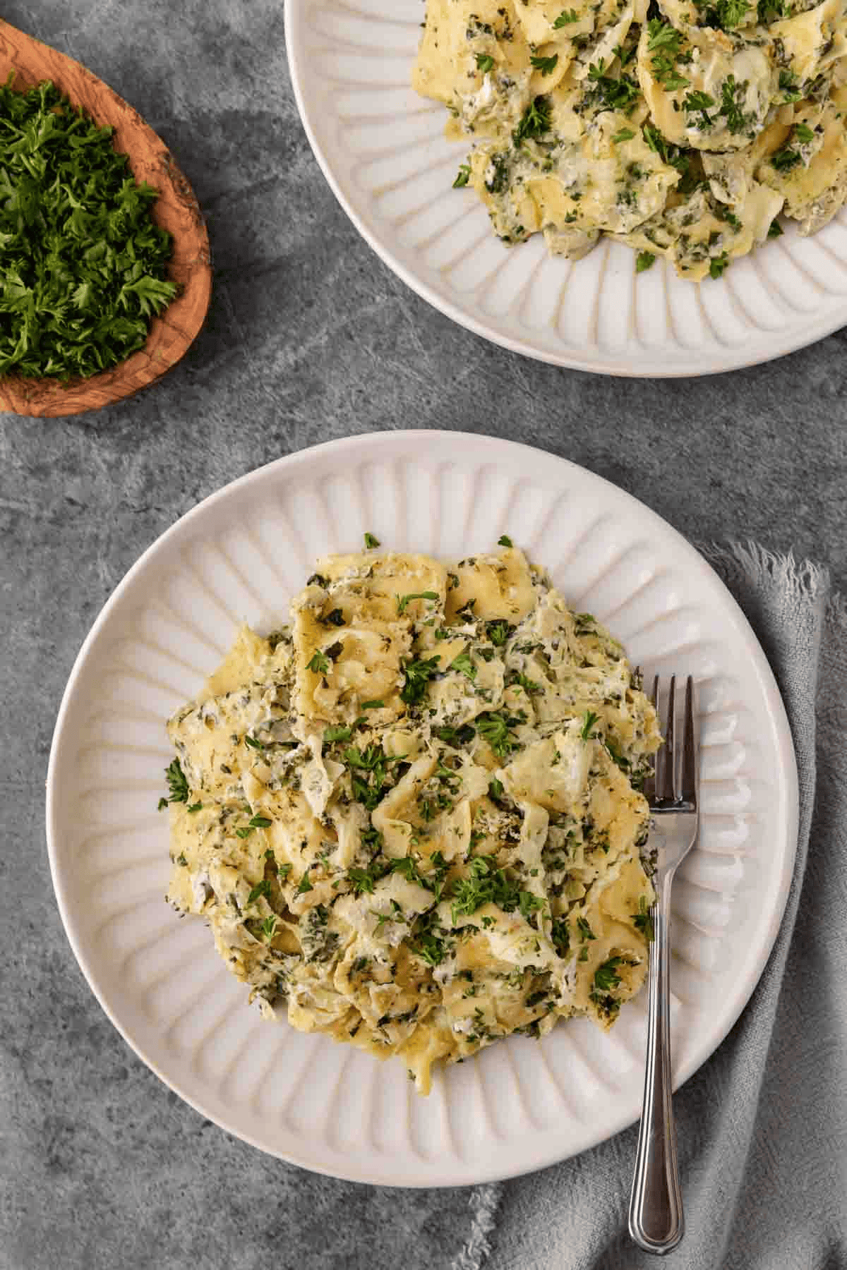 Serving of baked spinach, artichoke, and ravioli on a white plate