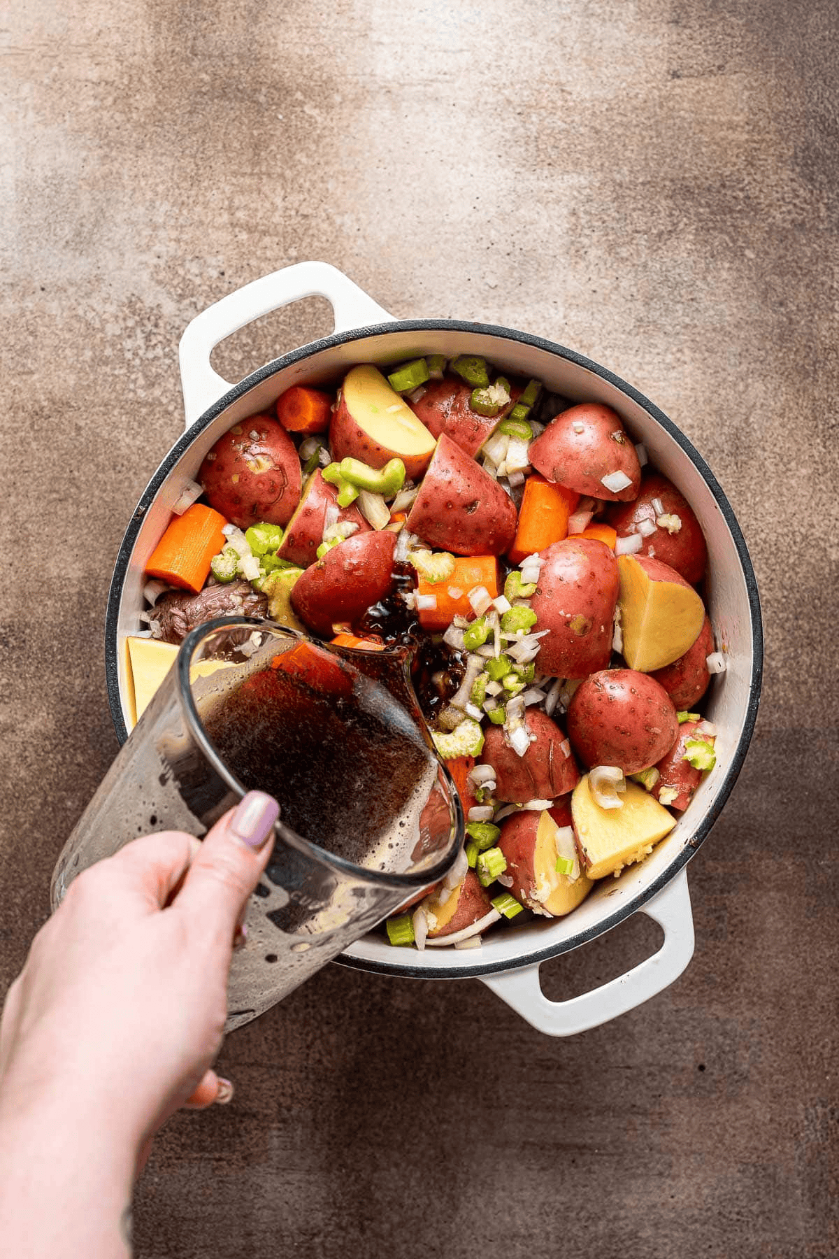 Adding vegetables and broth to a pot