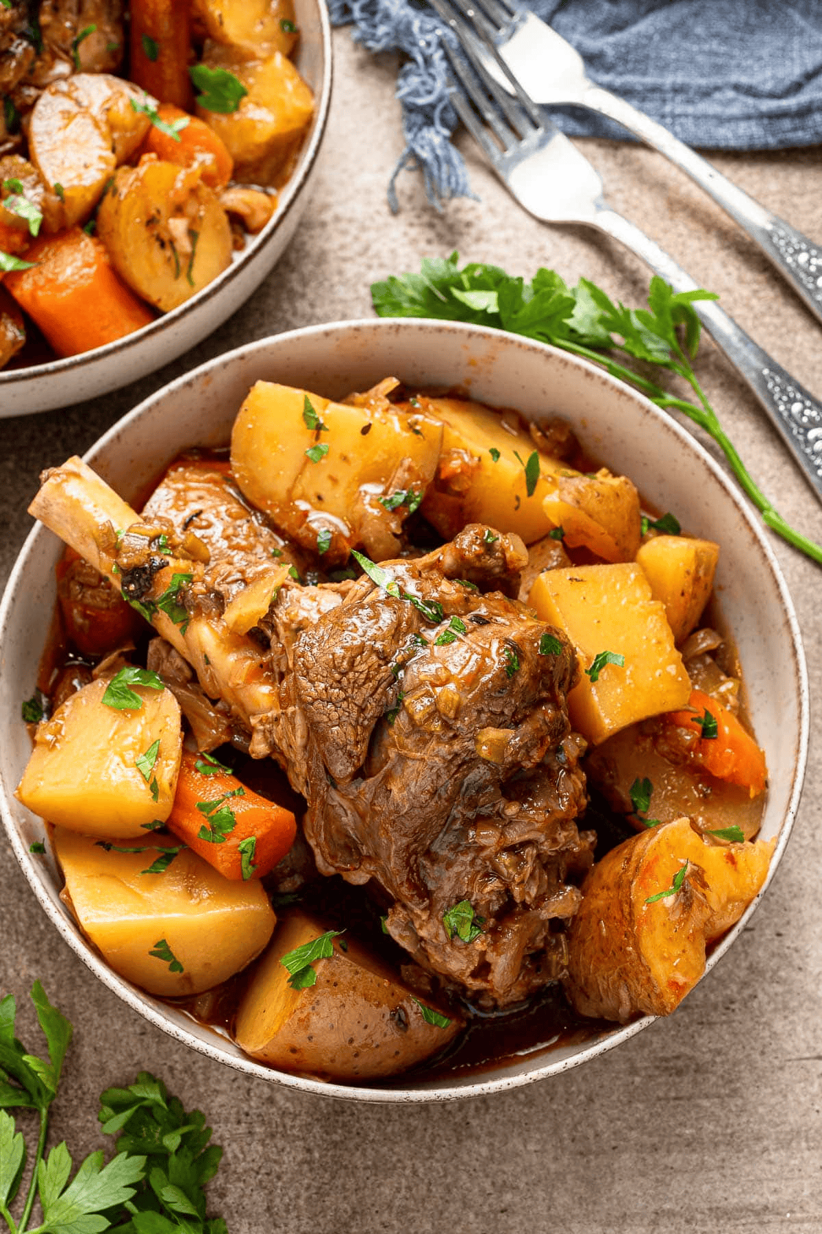 Lamb shank served over vegetables and carrots in a bowl