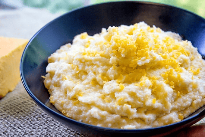 Creamy polenta topped in cheese in a blue bowl