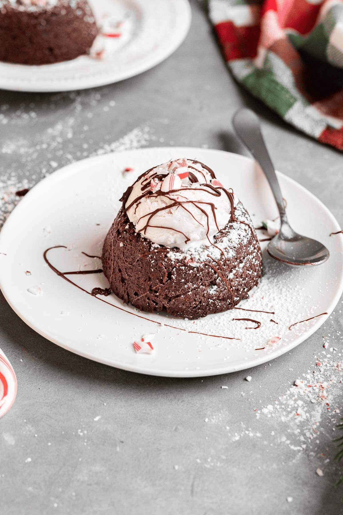 Chocolate cake topped in ice cream, chocolate drizzle, and peppermint pieces
