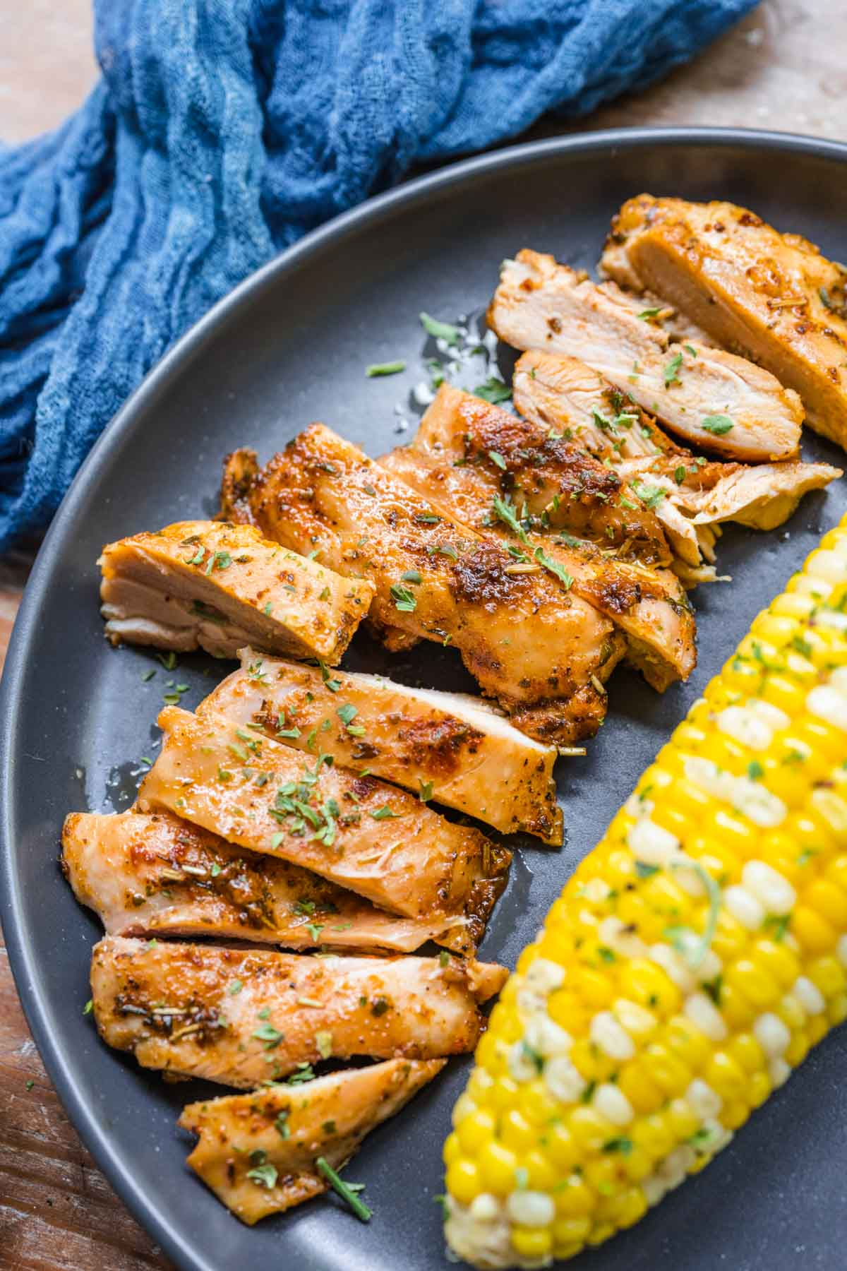 sliced chicken on a plate next to corn