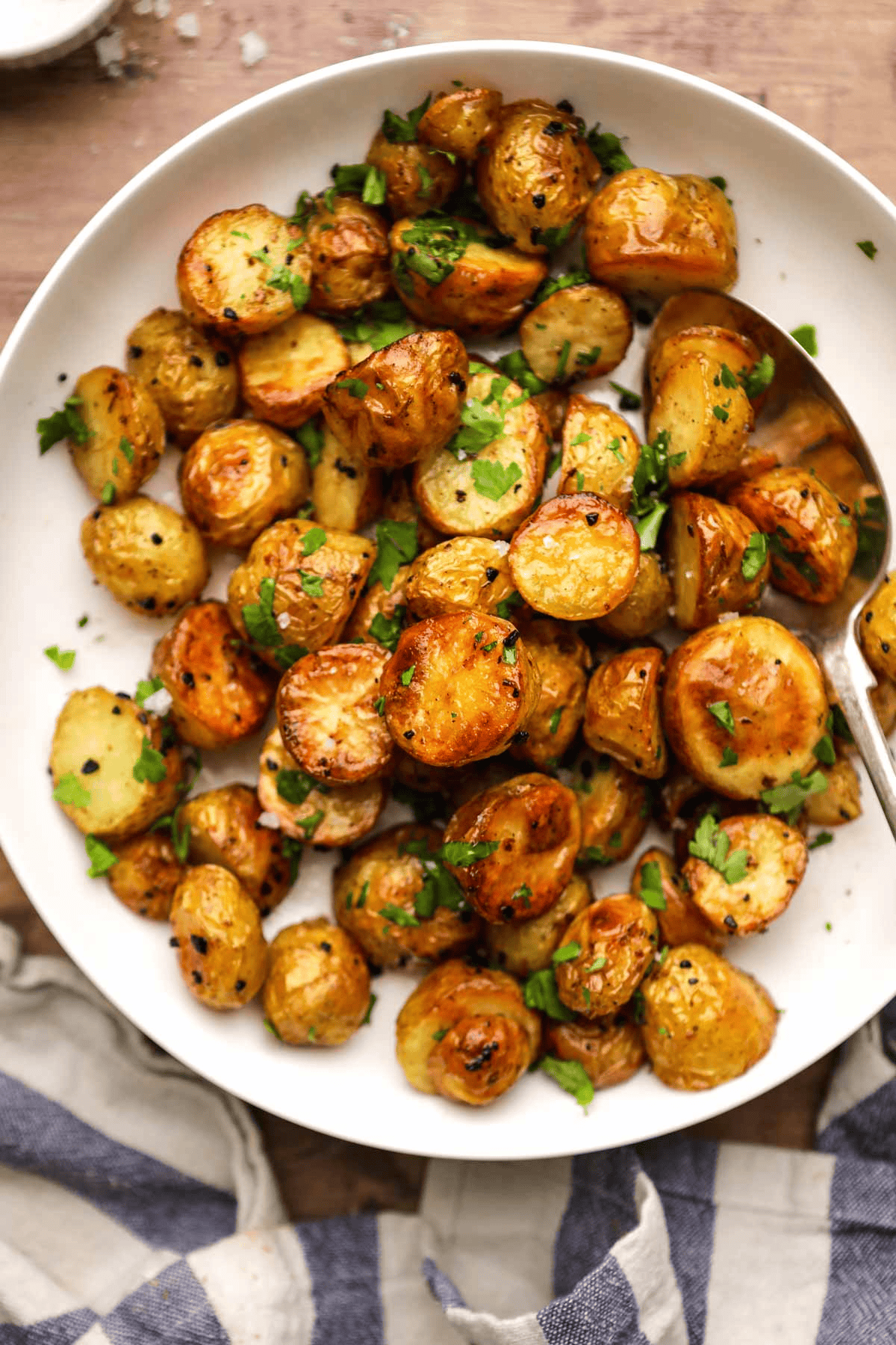 Golden baby potatoes in a white serving bowl with a spoon