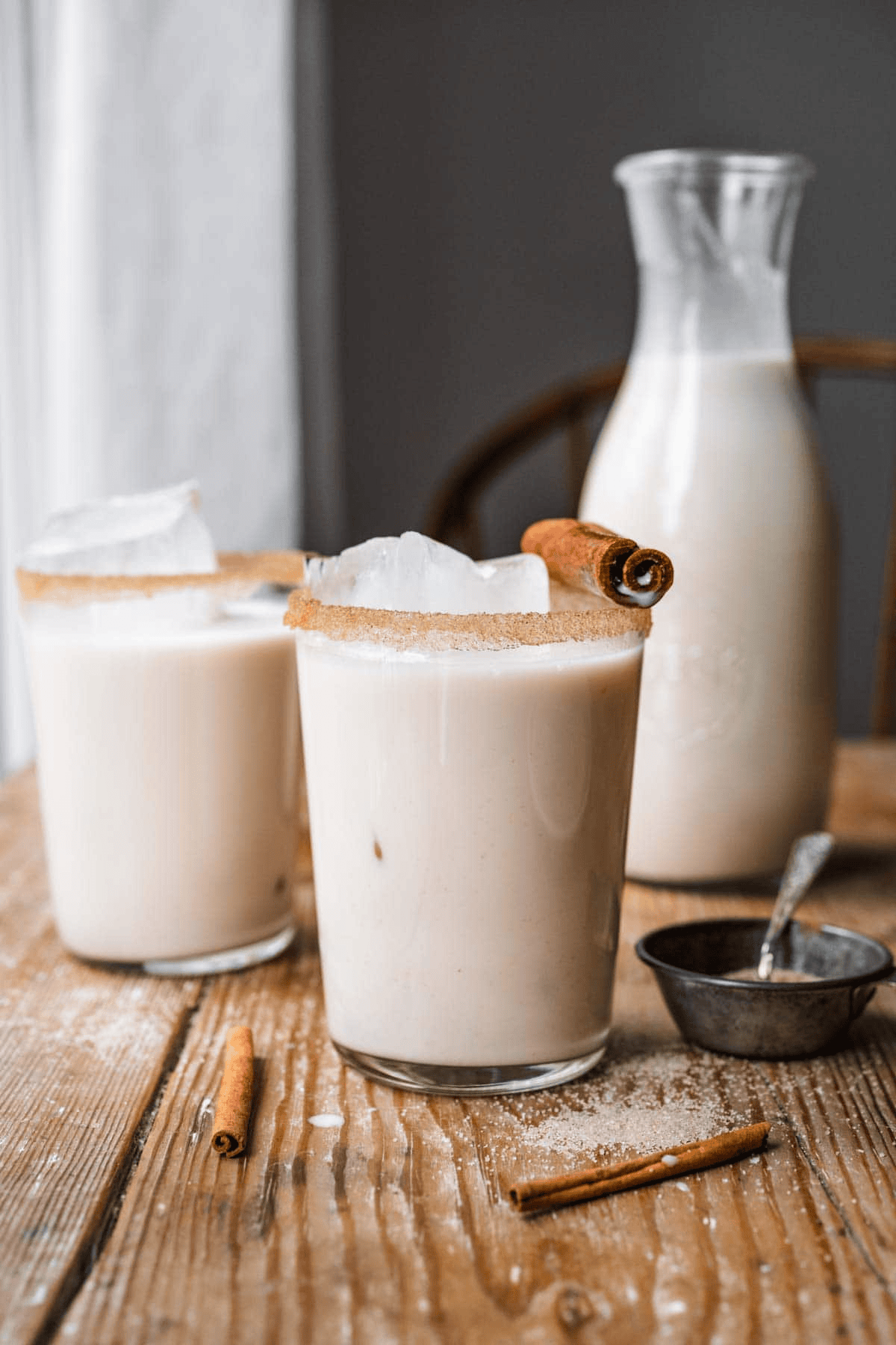 Two glasses of horchata with a glass bottle in the background
