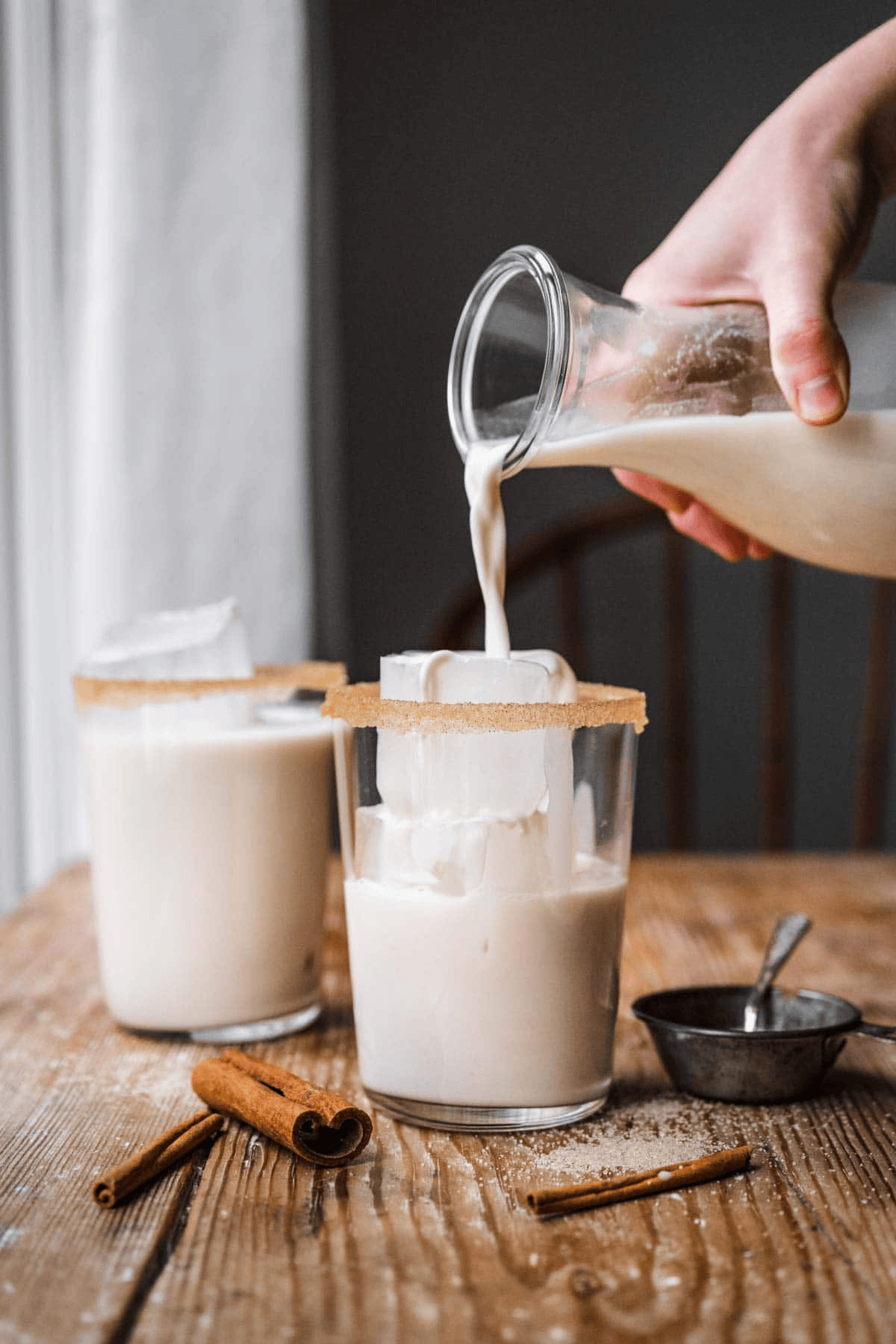 Pouring creamy drink into a glass with ice