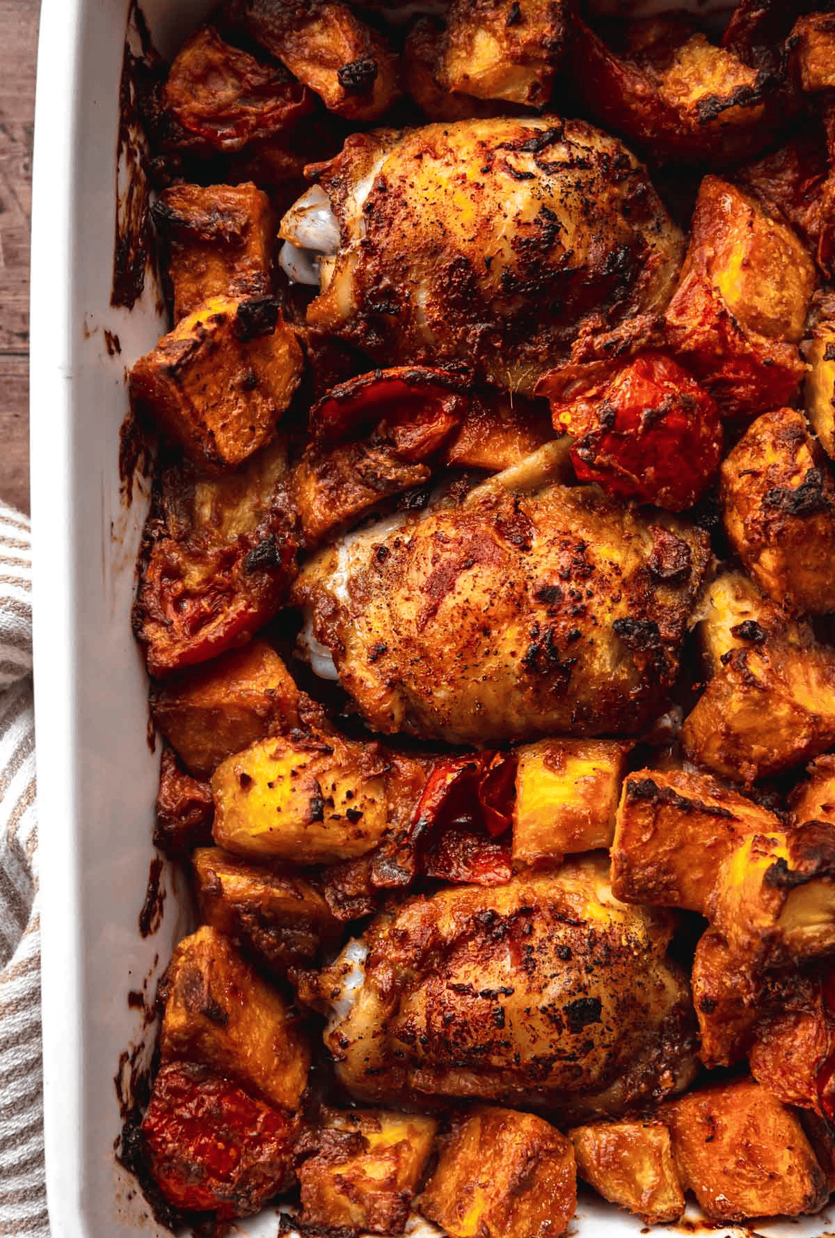 Baked chicken thighs and sweet potatoes in a white pan