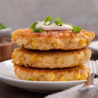 Three fried corn patties on appetizer plate.