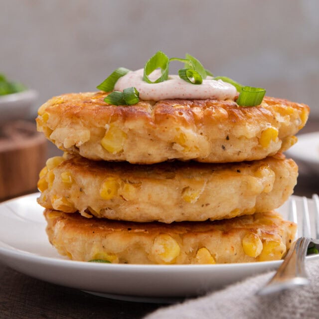Three fried corn patties on appetizer plate.