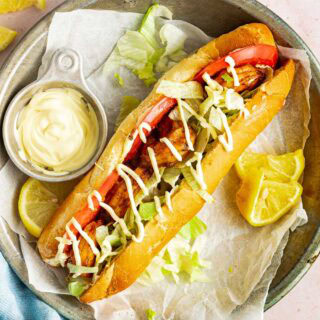 Plate with hoagie sandwich and a side of mayo.