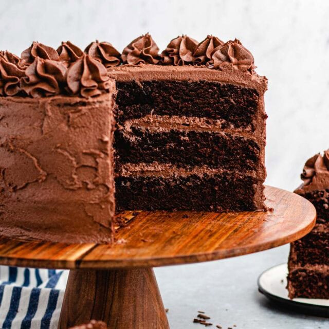 Whole cake on serving plate with piece taken out.