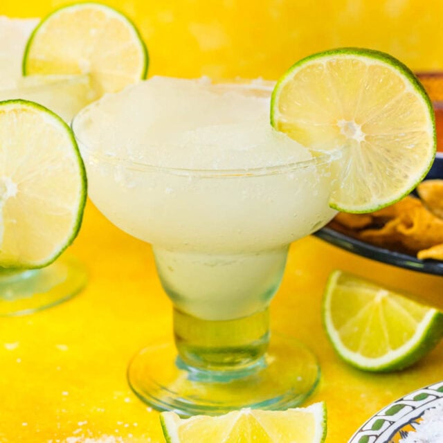 Blended frozen drink in glass with lime garnish.