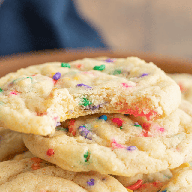 Sprinkle cookies stacked on top of each other with a bite taken out of the top cookie.