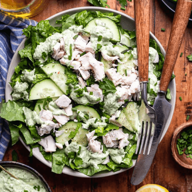 Salad on plate with creamy dressing and chicken.