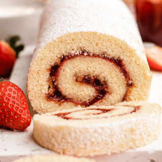 Finished rolled cake on a white platter garnished with strawberries
