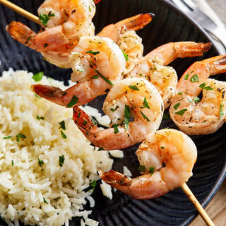 Dinner plate with rice and skewered shrimp.