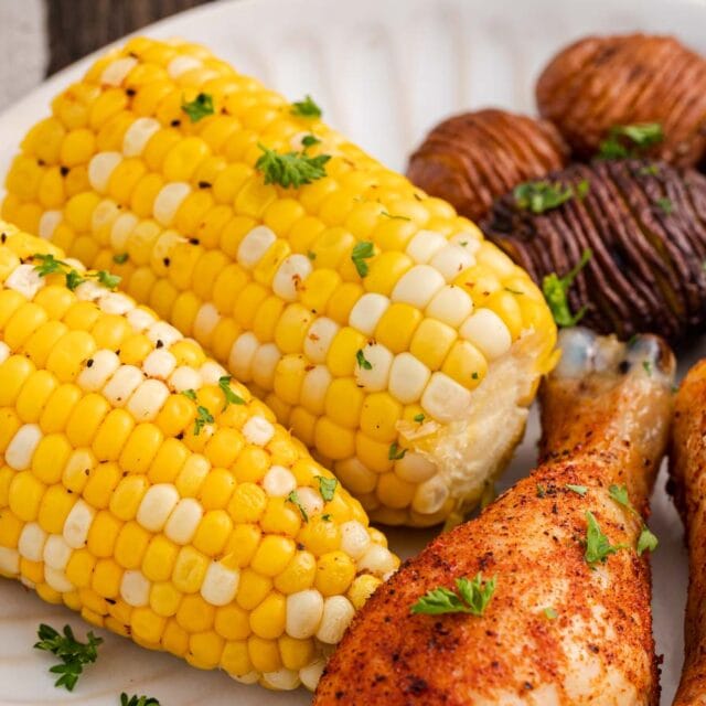 Dinner plate with corn on the cob, potatoes, and chicken.