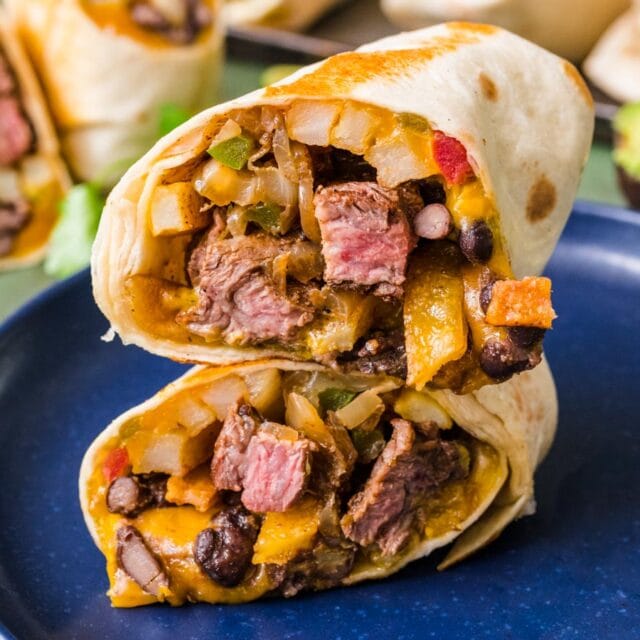 Burrito with beef, cheese, and veggies cut in half.