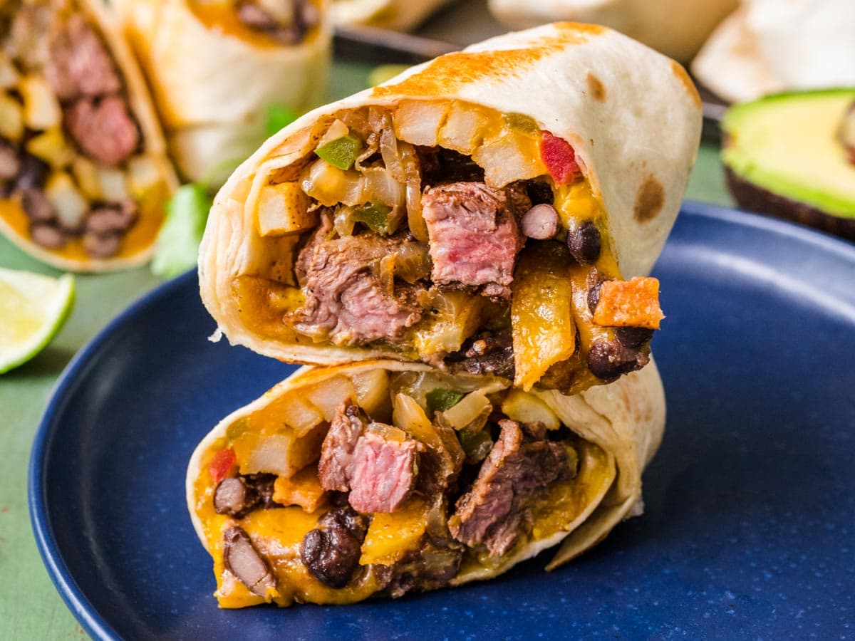Burrito with beef, cheese, and veggies cut in half.