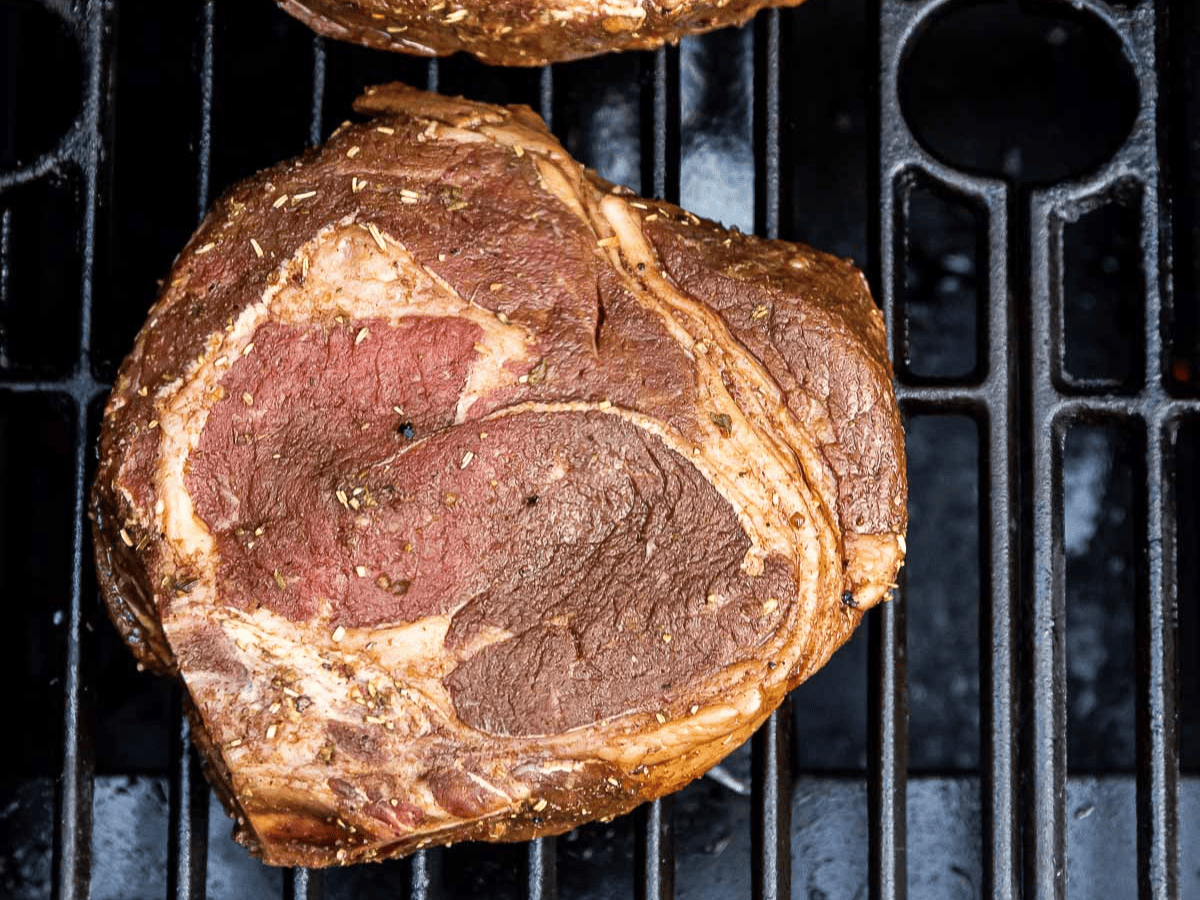 Raw marinated steak on grill.