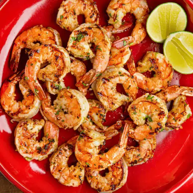 plate full of cooked citrus prawns with a citrus cut in half