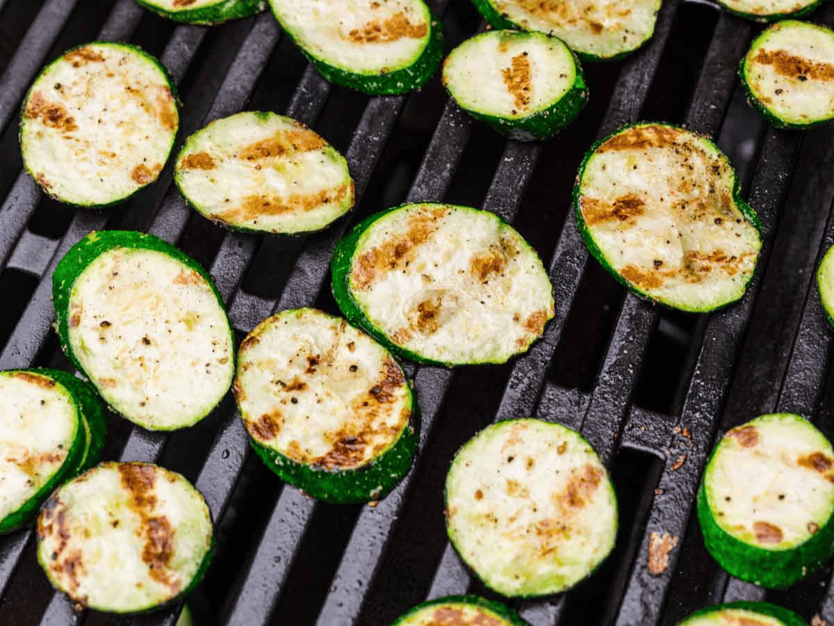 Slices of squash cooking on grill.