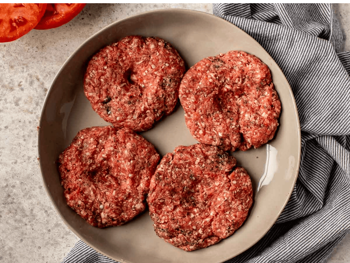 Raw, seasoned burger patties.