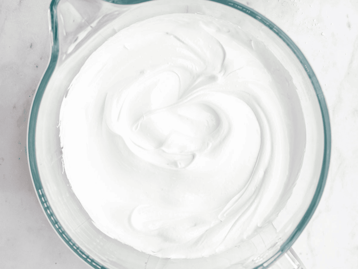 Mixing bowl with whipped egg whites, sugar, and corn syrup.