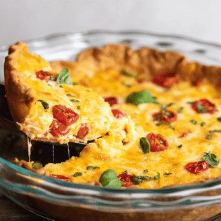Finished savory pie in a glass pie tin with red fruit, spices, cheese and egg.