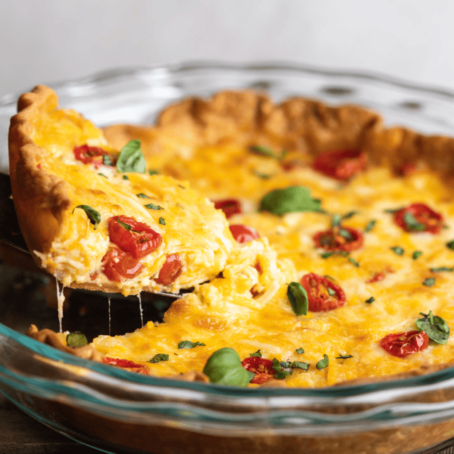 Finished savory pie in a glass pie tin with red fruit, spices, cheese and egg.