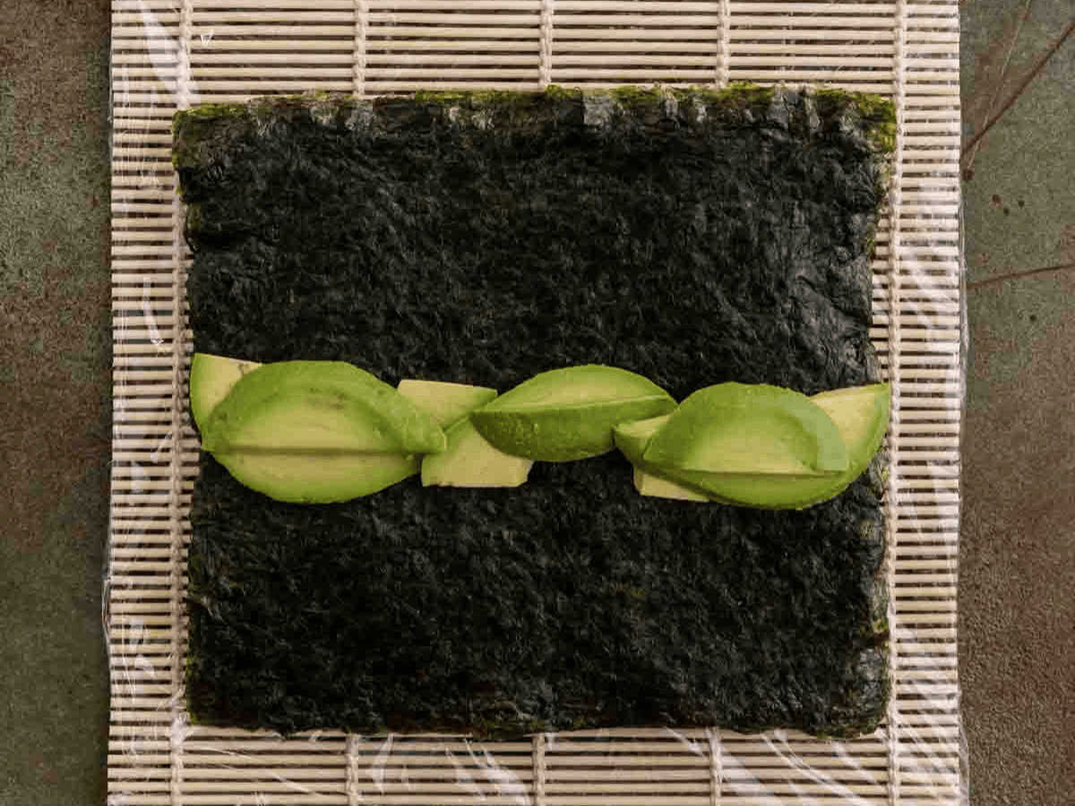 Sheet of seaweed and slices of avocado.