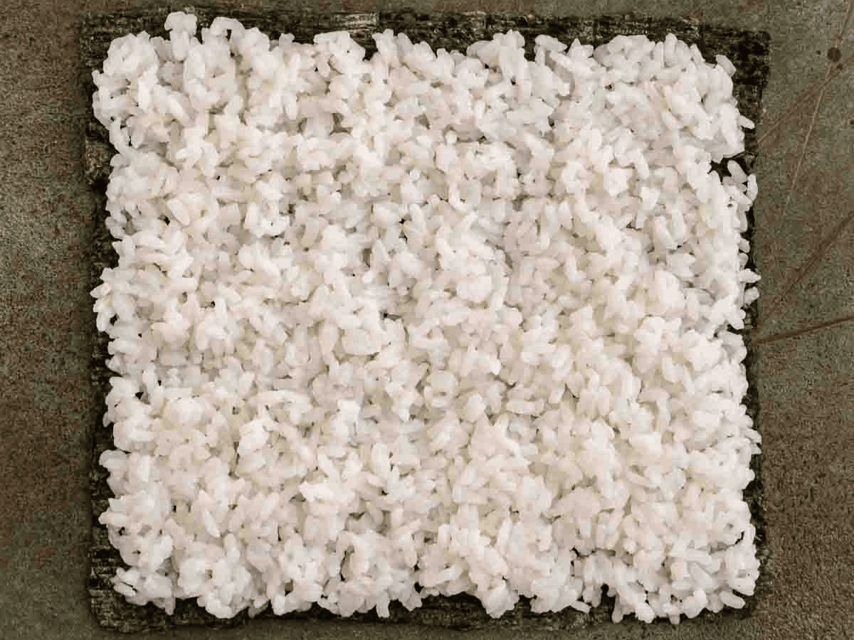 Rice spread out onto piece of seaweed.