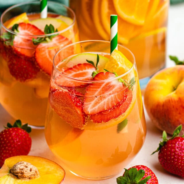 Wine cocktail in glass with fruit and straw.