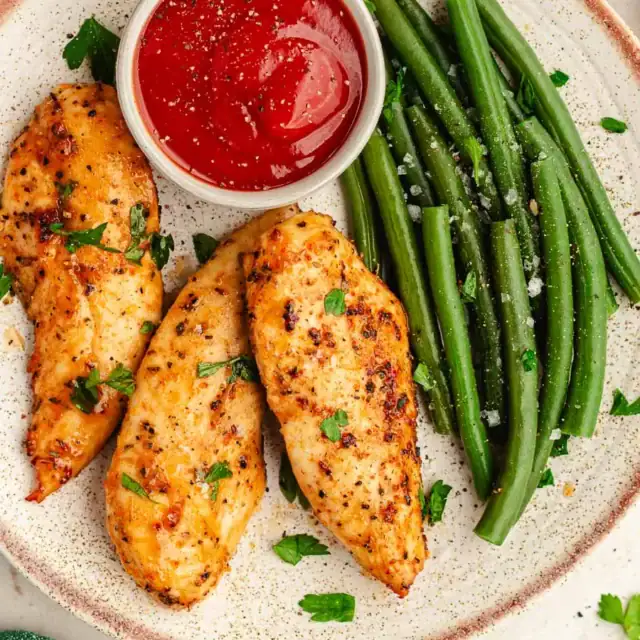 Seasoned and baked chicken with green beans on dinner plate.